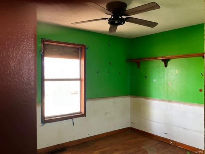 Unfurnished room with ceiling fan, visible vents, baseboards, and wood finished floors