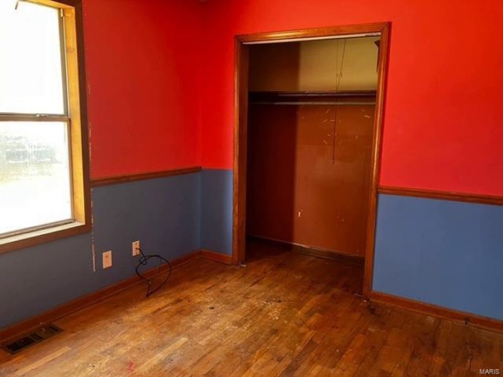 Unfurnished bedroom featuring a closet, visible vents, baseboards, and wood finished floors