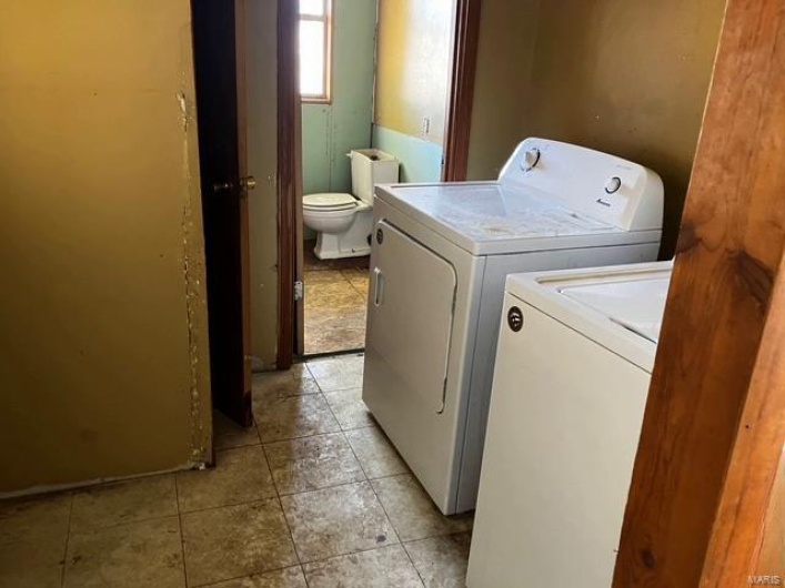 Washroom featuring washing machine and clothes dryer, laundry area, and light tile patterned flooring