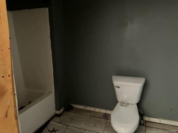 Bathroom with tile patterned floors, toilet, and baseboards