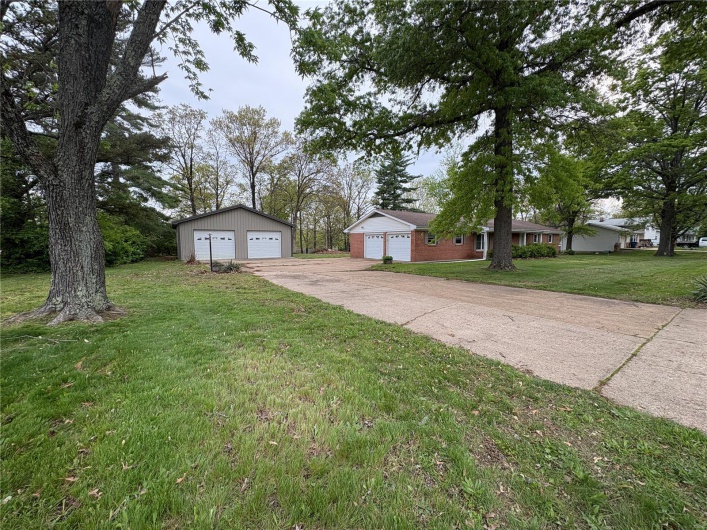 View of front of property with a detached garage, a front lawn, and an outbuilding