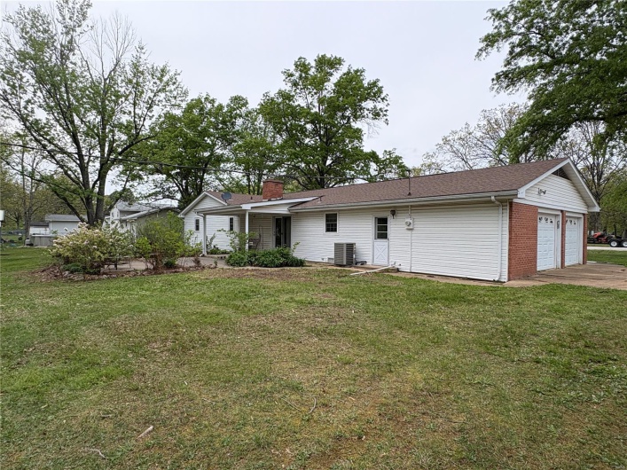 Back of property with a chimney, a lawn, and central air condition unit