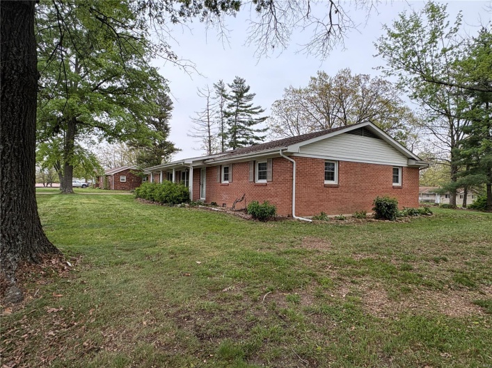 View of side of property featuring brick siding and a yard