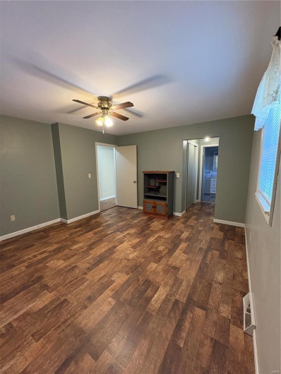 Unfurnished living room with ceiling fan and dark hardwood / wood-style flooring