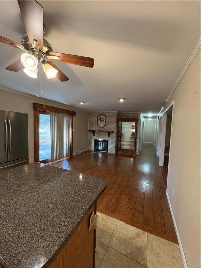 Kitchen featuring a fireplace, light hardwood / wood-style floors, ornamental molding, refrigerator, and ceiling fan