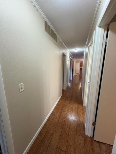 Corridor with ornamental molding and dark hardwood / wood-style flooring