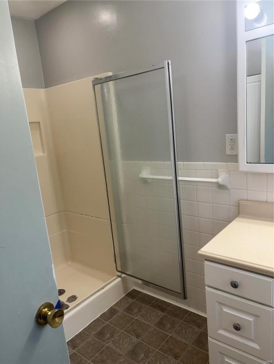 Bathroom with tile walls, a shower with door, and vanity