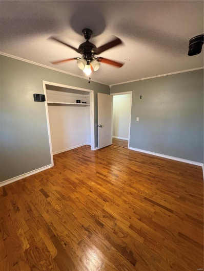 Unfurnished bedroom with ceiling fan, crown molding, a textured ceiling, and wood-type flooring