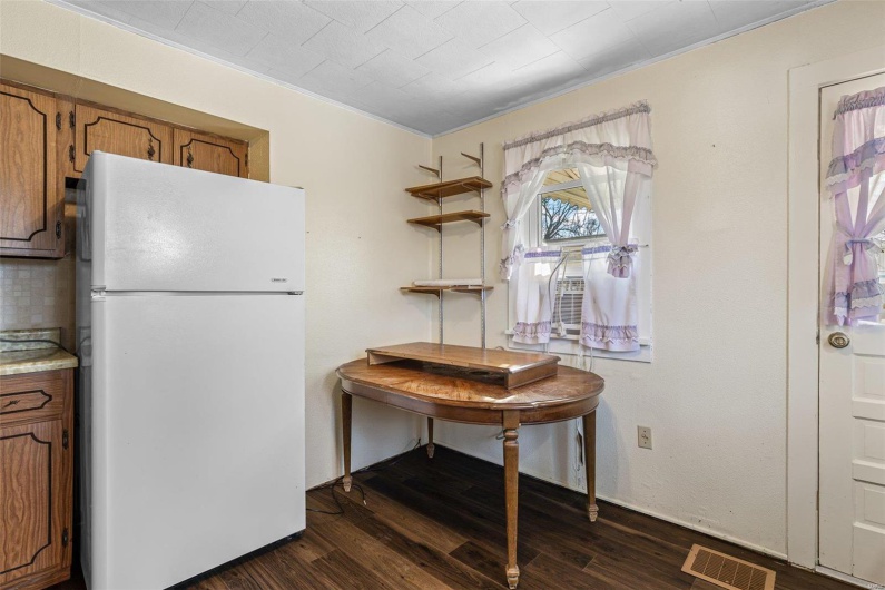Kitchen featuring dark wood-style floors, visible vents, brown cabinets, and freestanding refrigerator