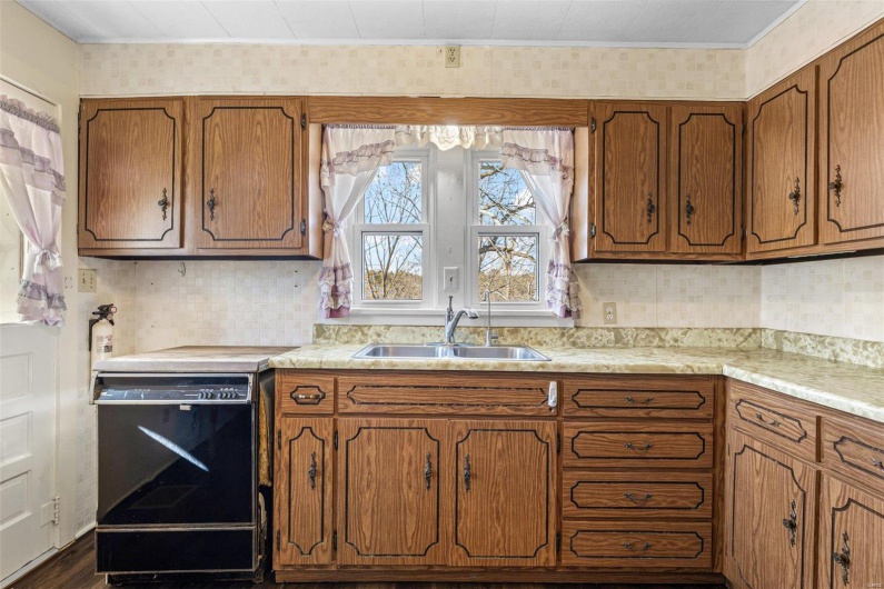 Kitchen featuring a sink, dishwasher, brown cabinetry, and light countertops