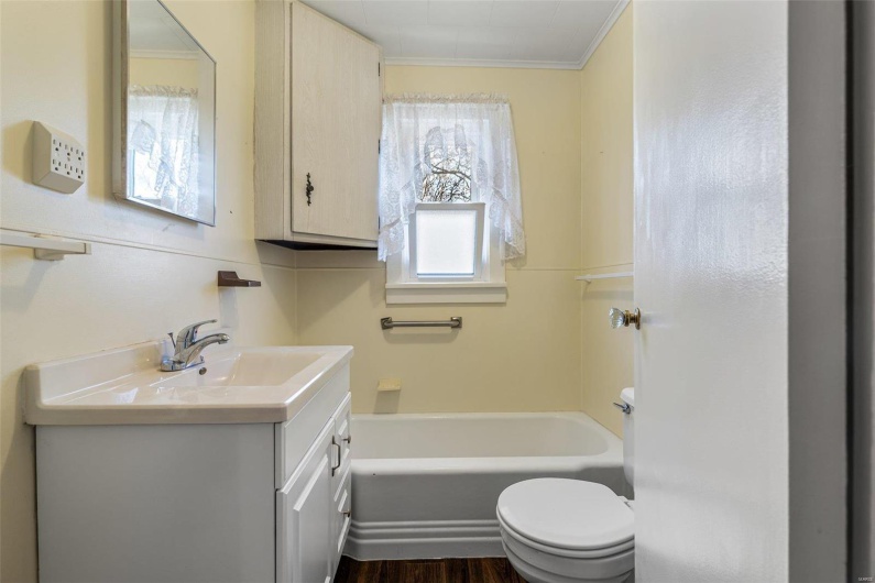 Bathroom with toilet, ornamental molding, a bathing tub, wood finished floors, and vanity