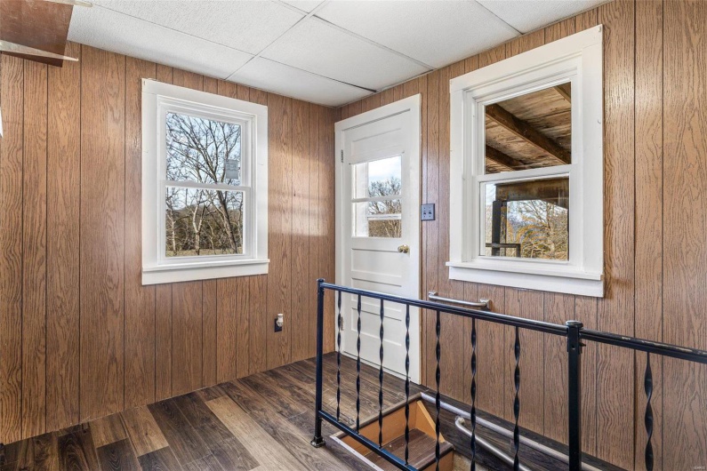 Stairway featuring a drop ceiling, wood finished floors, and wood walls