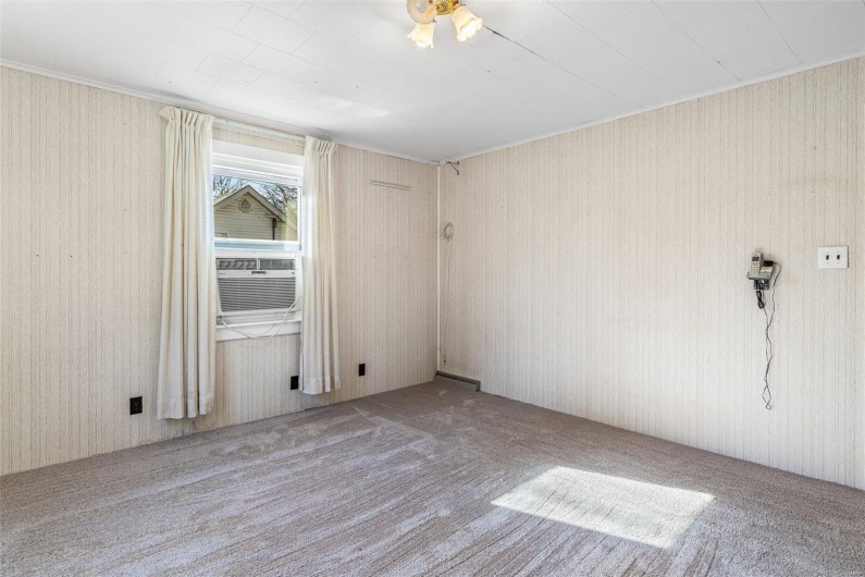 Carpeted spare room featuring cooling unit