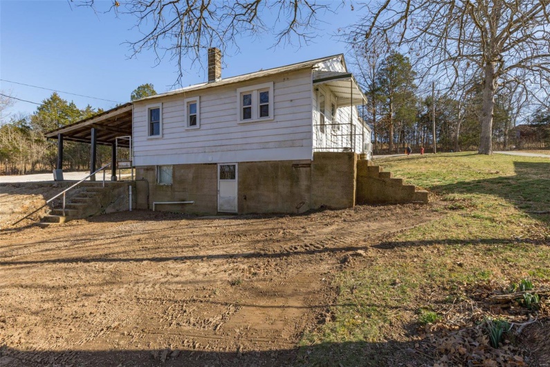 Rear view of house with a yard, driveway, a carport, and a chimney