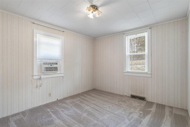 Carpeted empty room with cooling unit and visible vents
