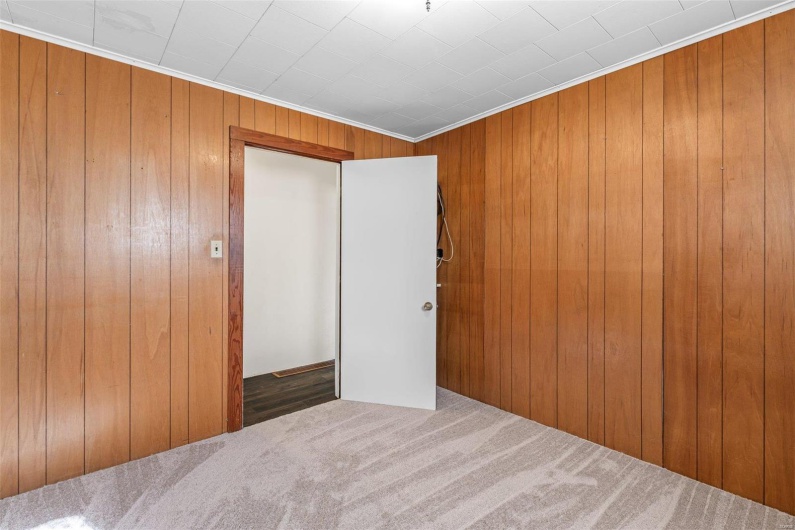 Unfurnished bedroom with a closet, wood walls, and carpet