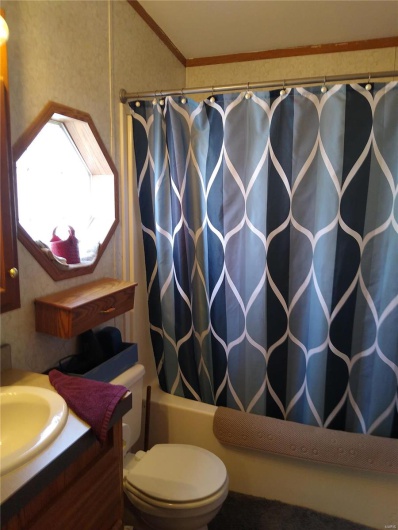 Full bath featuring shower / bath combo with shower curtain, vanity, toilet, and crown molding