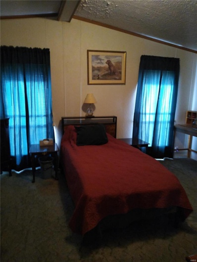 Carpeted bedroom with a textured ceiling, ornamental molding, and vaulted ceiling