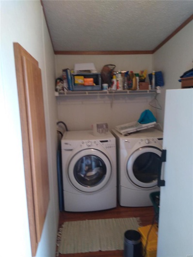Laundry area with ornamental molding, a textured ceiling, wood finished floors, separate washer and dryer, and laundry area