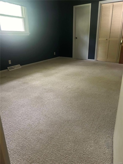 Unfurnished bedroom with visible vents, carpet, and a closet