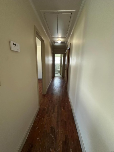 Hall featuring visible vents, baseboards, dark wood finished floors, attic access, and ornamental molding