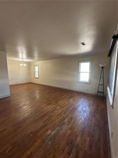 Empty room featuring a wealth of natural light, visible vents, baseboards, and dark wood-type flooring
