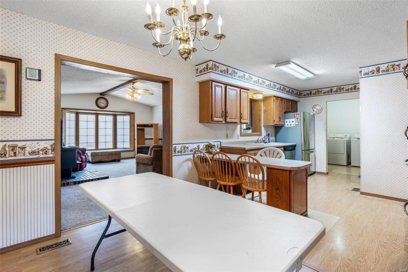 Kitchen featuring washer and clothes dryer, a textured ceiling, wallpapered walls, and a kitchen breakfast bar