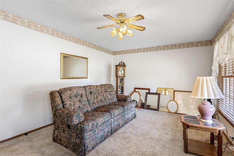 Living room featuring baseboards, carpet, ceiling fan, and a textured ceiling