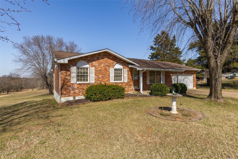 Single story home featuring a garage, brick siding, and a front lawn