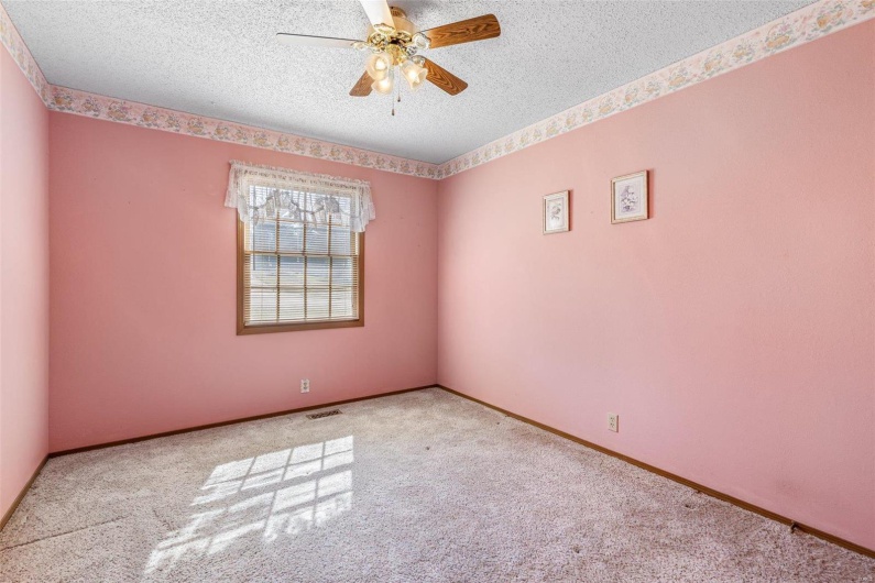 Carpeted spare room with ceiling fan, visible vents, baseboards, and a textured ceiling