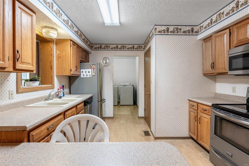 Kitchen featuring visible vents, wallpapered walls, washer and dryer, stainless steel appliances, and a sink