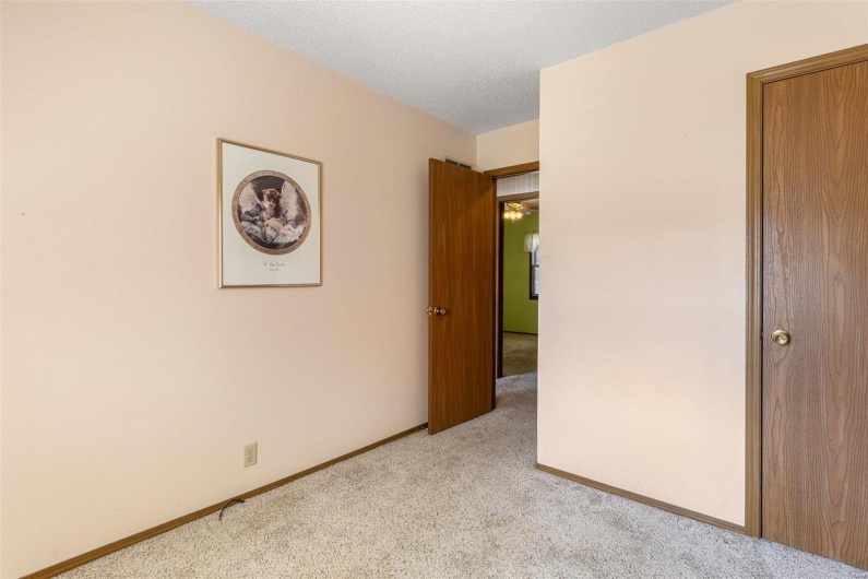 Unfurnished bedroom with light carpet, a textured ceiling, and baseboards