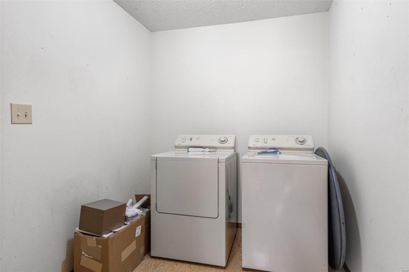Clothes washing area featuring laundry area, light wood-style flooring, independent washer and dryer, and a textured ceiling