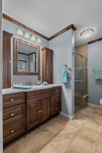 Full bathroom featuring toilet, a stall shower, a textured ceiling, crown molding, and vanity