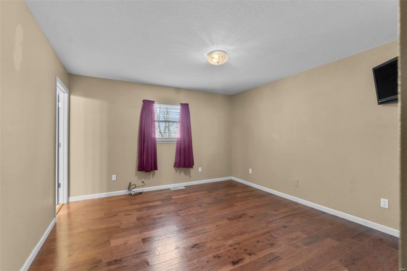 Empty room featuring visible vents, baseboards, and wood finished floors