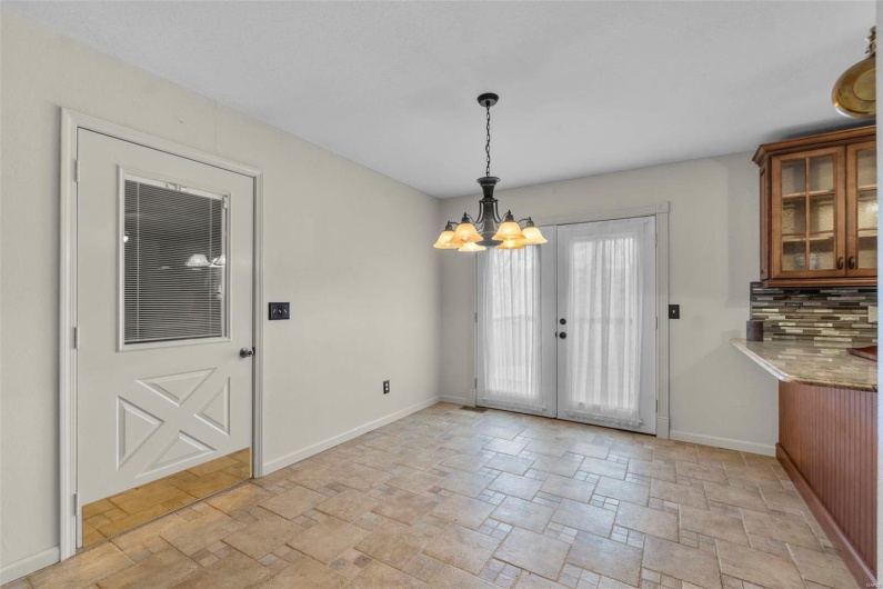 Unfurnished dining area with baseboards, a chandelier, and stone finish floor