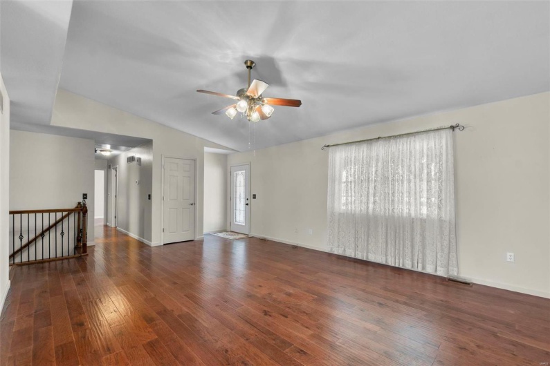 Unfurnished living room with vaulted ceiling, baseboards, ceiling fan, and hardwood / wood-style floors