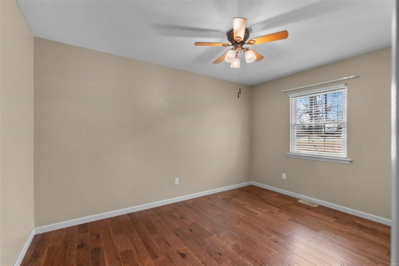 Unfurnished room with dark wood-style floors, visible vents, baseboards, and a ceiling fan