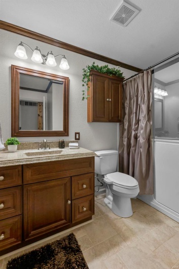 Full bath featuring vanity, a shower with curtain, visible vents, ornamental molding, and toilet
