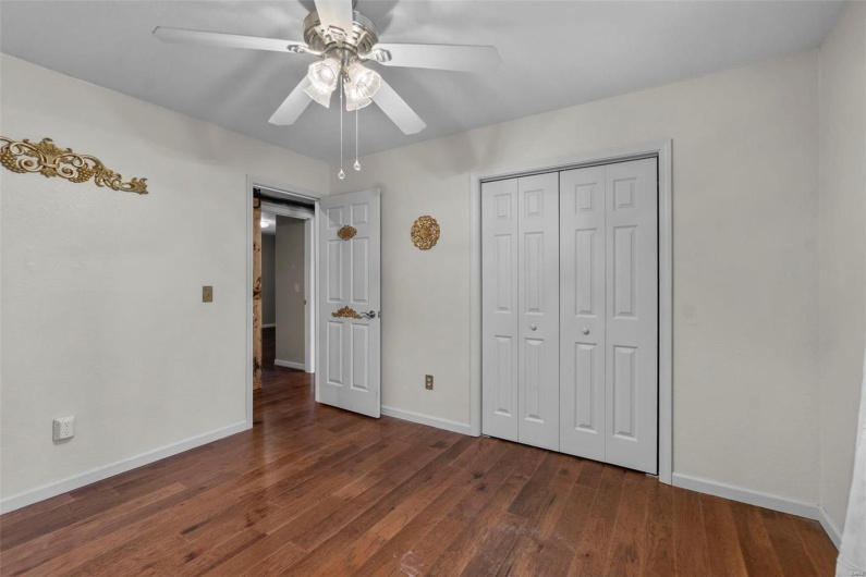 Unfurnished bedroom featuring wood finished floors, baseboards, a closet, and ceiling fan