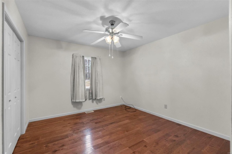 Unfurnished bedroom with visible vents, ceiling fan, baseboards, hardwood / wood-style floors, and a closet