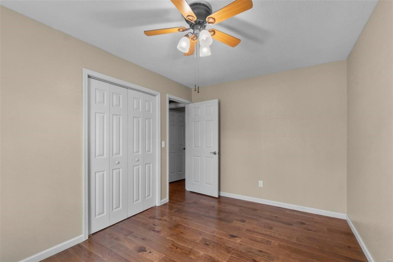 Unfurnished bedroom featuring a ceiling fan, wood finished floors, baseboards, and a closet