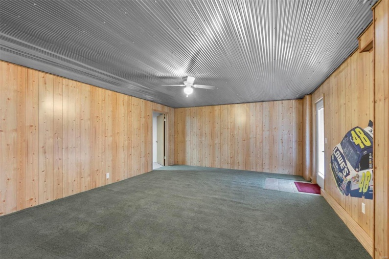 Carpeted spare room with wooden walls and a ceiling fan
