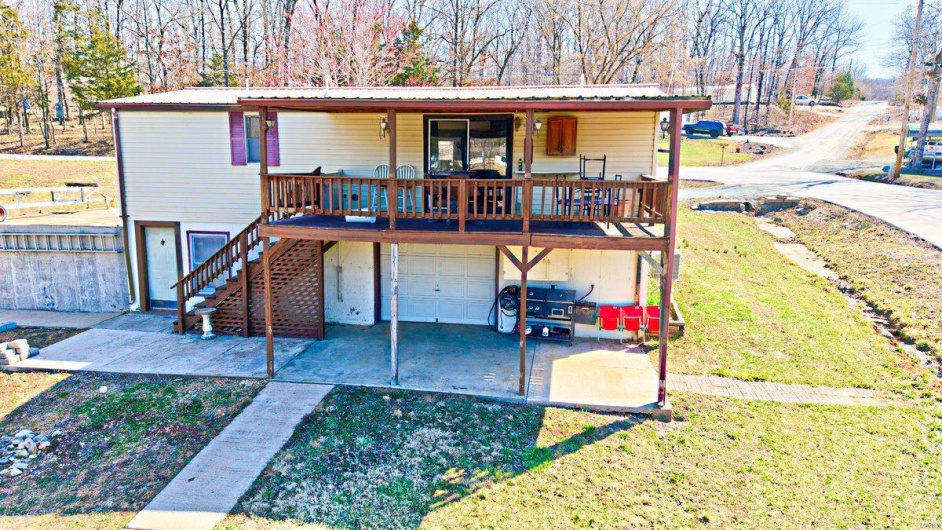 View of front of house featuring driveway, a porch, stairway, metal roof, and a garage