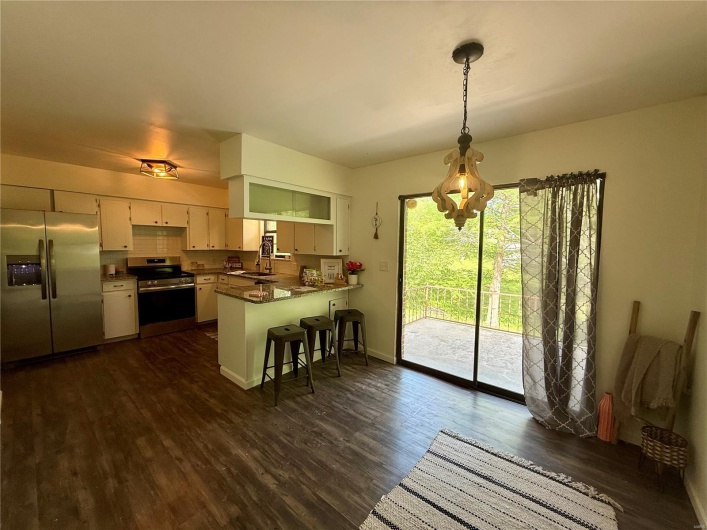 Kitchen with a peninsula, dark countertops, stainless steel appliances, white cabinets, and dark wood-type flooring