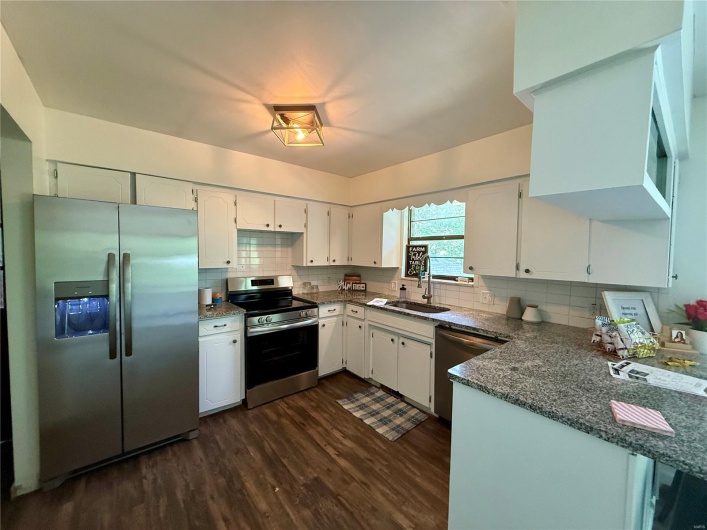Kitchen with appliances with stainless steel finishes, dark wood-style flooring, tasteful backsplash, and a sink