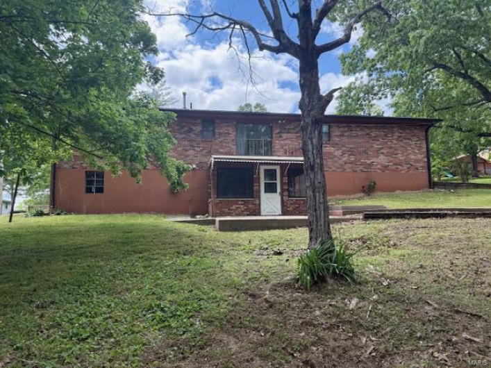 Back of property with a yard and brick siding