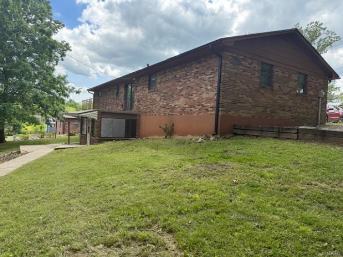 View of side of property with a yard and brick siding