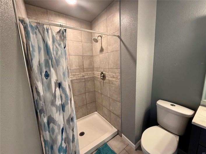 Full bath featuring a stall shower, tile patterned floors, and toilet