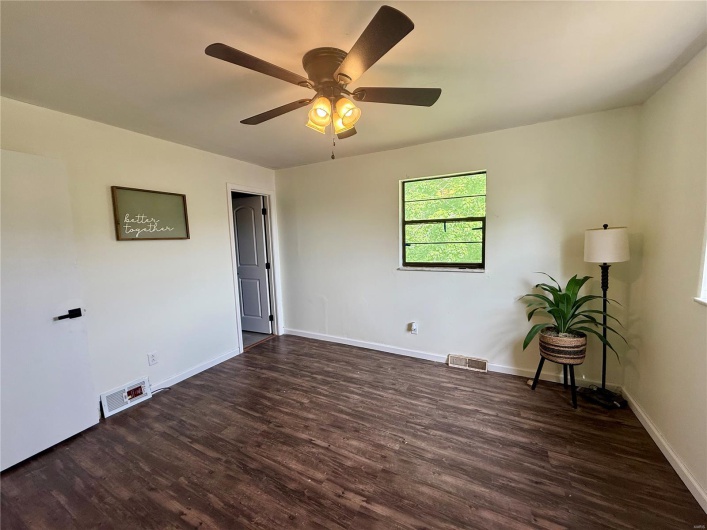 Empty room featuring ceiling fan, baseboards, visible vents, and wood finished floors
